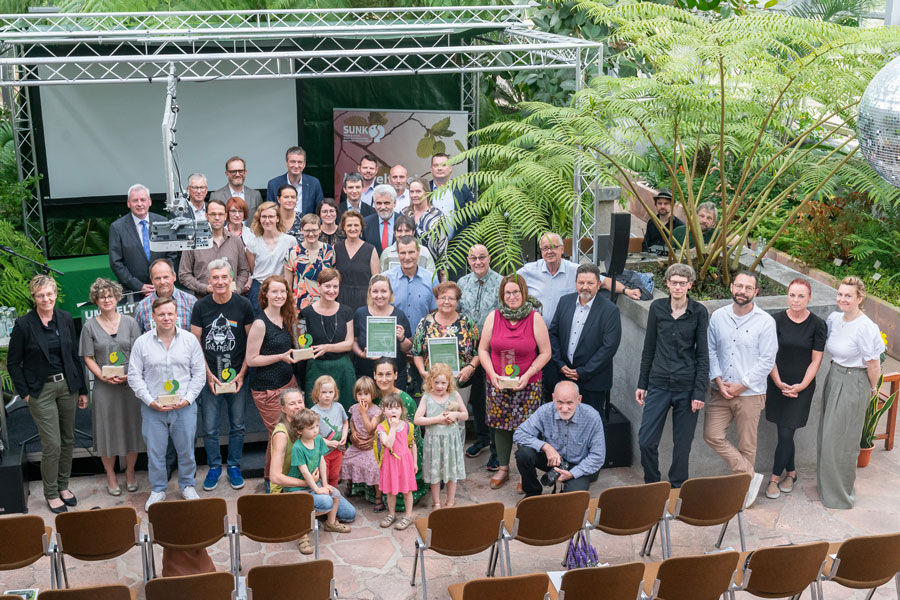 Menschen stehen vor einer Bühne und blicken in die Kamera