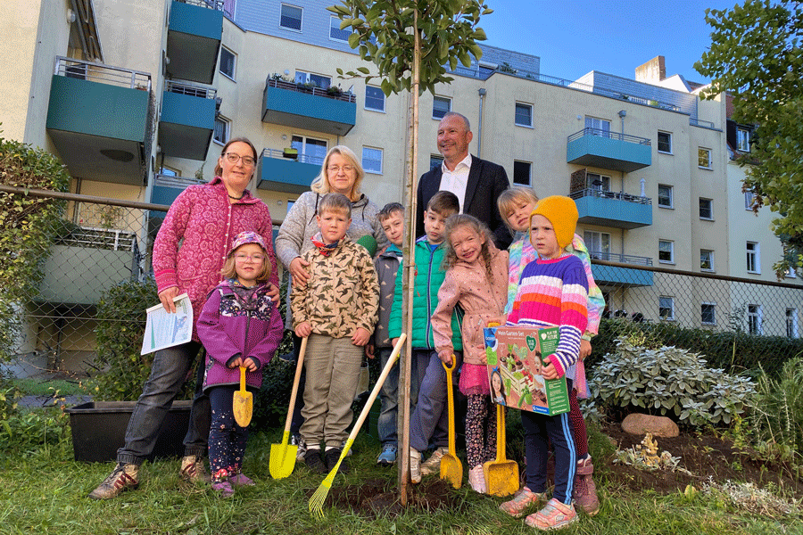 Die Kinder, Erzieherinnen und EVH-Geschäftsführer Olaf Schneider stehen an dem neuen Baum.