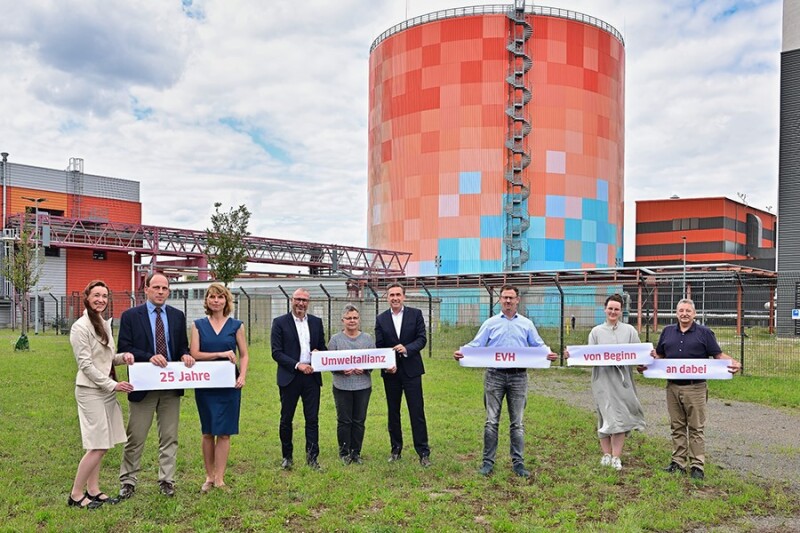 Vertreter aus Politik und Wirtschaft halten 25 Jahre Banner vor dem Kraftwerk.