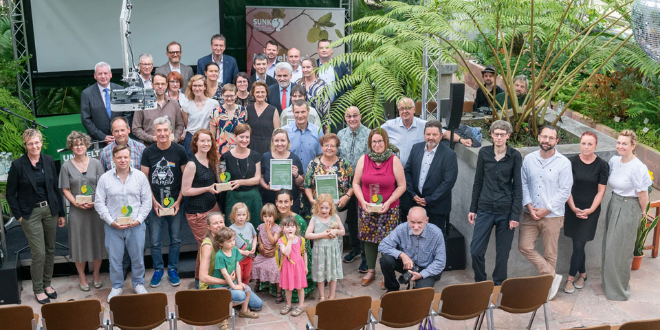 Menschen stehen vor einer Bühne und blicken in die Kamera
