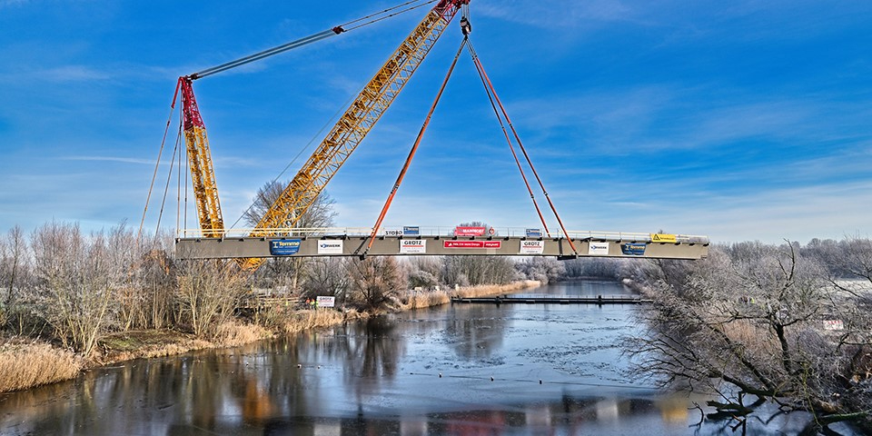 Kran hebt Brücke über den Kanal.