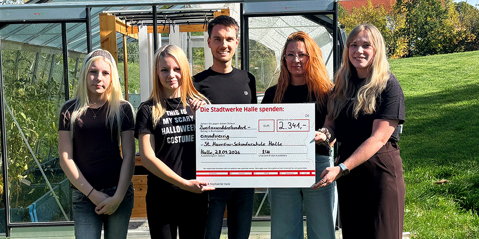 Fünf Personen stehen vor einem Gewächshaus und halten einen Spendenscheck in der Hand.