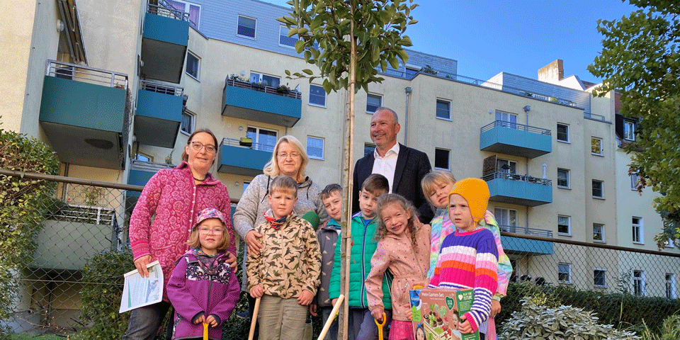 Die Kinder, Erzieherinnen und EVH-Geschäftsführer Olaf Schneider stehen an dem neuen Baum.