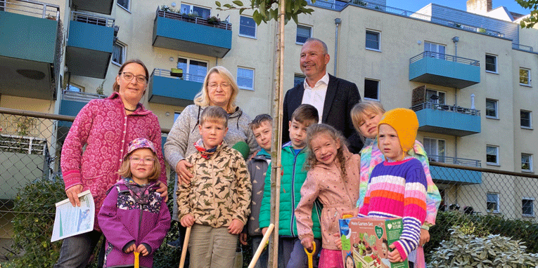 Die Kinder, Erzieherinnen und EVH-Geschäftsführer Olaf Schneider stehen an dem neuen Baum.