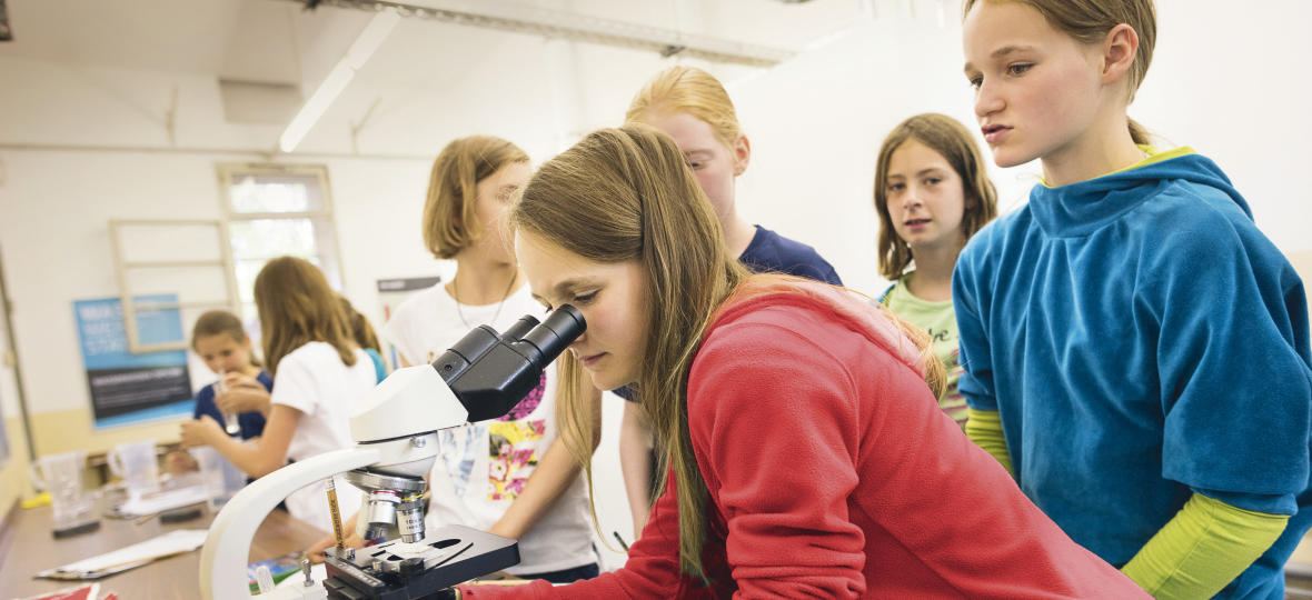Das Bild zeigt Schülerinnen in der Wasserwerkstatt des Historischen Technikzentrums der Stadtwerke Halle. Im Vordergrund schaut eines der Mädchen in ein Mikroskop, weiter hinten werden weitere Experimente mit Wasser durchgeführt.