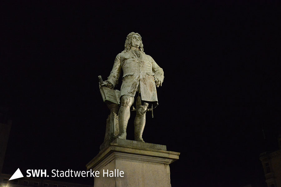 Das Händel-Denkmal auf dem Marktplatz wird angestrahlt. Die Nahaufnahme zeigt einen schwarzen Hintergrund, da es Nacht ist.