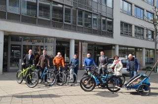 Die an der Kampagne beteiligten Personen stehen vor dem Stadtwerke-Gebäude für ein Gruppenfoto zusammen. Alle haben ein E-Bike der neuesten Generation in der Hand.