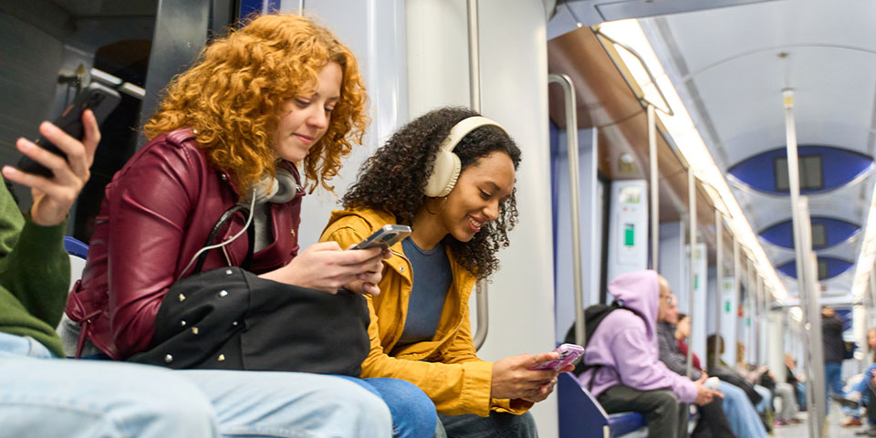 Junge Leute schauen auf Ihre Smartphones während Sie mit dem öffentlichen Nahverkehr unterwegs sind