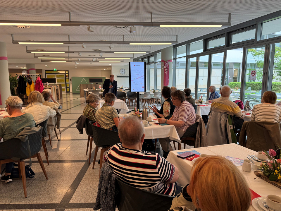 Seniorinnen und Senioren sitzen in der Kantine der Stadtwerke Halle und lauschen dem Referenten
