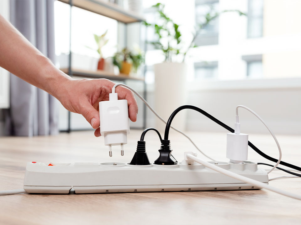 An eine weiße Mehrfachsteckdose wird ein USB-Ladegerät angeschlossen